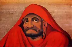 Bearded figure in a vivid red robe with solemn expression and hoop earring