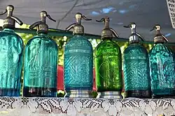A row of colorful soda siphons on a shelf