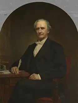 Elderly man in 19th-century formal dress seated and holding a quill