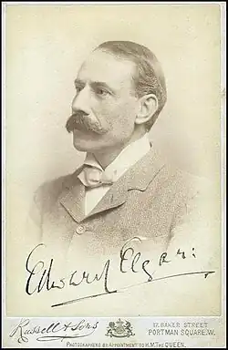middle-aged white man with neat dark hair and large moustache seen in left semi-profile