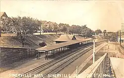 Postcard of a below-grade railway station with a small depot building