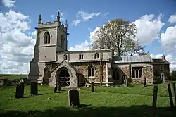 A stone church seen from the south with a battlemented tower to the left and a smaller chancel to the right