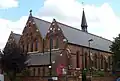 St Thomas's Church, Islington, London, 1888–89 by Ewan Christian, view of west front and south aisle showing Early English style lancets and narthex below the west windows[161]