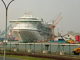 A cruise ship being repaired is photographed in the distance