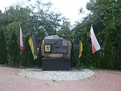 A commemorative stone surrounded by the flag of Kashubia and Poland