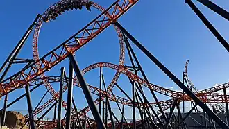 Twisted orange rollercoaster track, the train is travelling through a large loop.