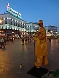 A Street artist at Puerta del Sol and the Tío Pepe Neon Advertisement photographed at Sunset.