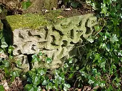 A stone with recessed markings from the ornate footbridge.
