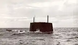 Port side view of the sail and forward deck of the nuclear submarine Triton breaking the surface of the ocean near Cádiz, Spain, with hull number 586 visible on its sail.