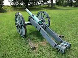 Photo shows an 18th-century cannon mounted on a blue-grey painted gun carriage.
