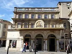 exterior of theatre in neo-classical style, with British royal arms over the main entrance