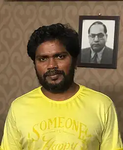 Pa. Ranjith in home in front of a photo