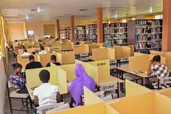Students studying in cubicles with bookshelves behind them