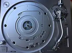 A Technics SL-1200G with the platter removed reveals the top of the newly designed coreless direct drive motor assembly. The platter has no magnet ring on the backside, but is directly bolted onto the motor assembly, instead using three flathead bolts.