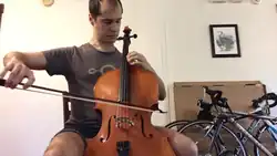 A man playing a tenor violin of the Violin octet family, in a sitting position.