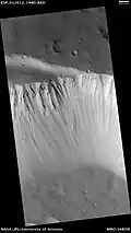 HiRISE image of the northwestern wall of Tharsis Tholus caldera. Note the outcrops of bedrock at top.