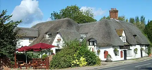 English pub names such as The Barley Mow (like this pub at Clifton Hampden) allude to the use of barley to make the beer available inside.[104]