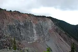 A vertical rocky cliff with a steep-sided rubble deposit at the base