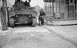 A Dutch civilian lifts his two children away from danger near a Sherman tank during fighting in 's-Hertogenbosch
