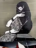 Black-and-white mural with a stylized woman in a traditional Peruvian saya y manto, with her face partially veiled and surrounded by floral and starry patterns.