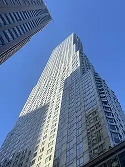 A picture of a tall skyscraper taken from the ground facing upwards towards the sky