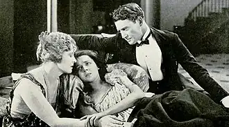 Black and white film still showing three actors in 1920s period costumes