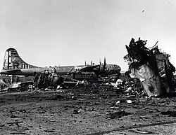 A black and white photograph of the wreckage of a plane after an explosion, another intact plane can also be seen