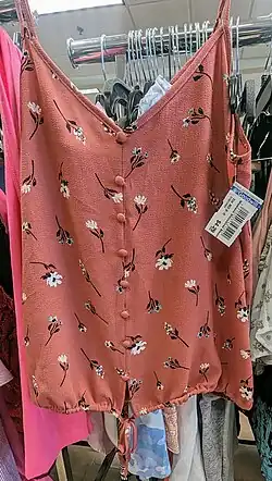 A floral summer top/blouse on hanger inside of a thrift store, with price tags listed at $4.29.