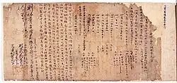 Japanese or Chinese text and red stamp marks on brown damaged paper.