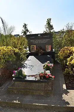 Gravestone reading the names of Ferrer, Ascaso and Durruti, covered in flowers and photographs of dead anarchist fighters