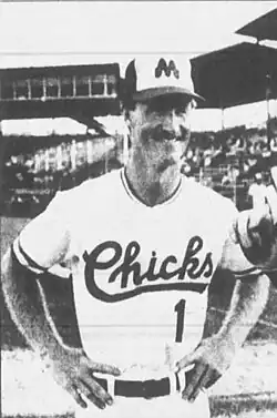 A man wearing a white baseball uniform and a black and white cap with a dark "M".