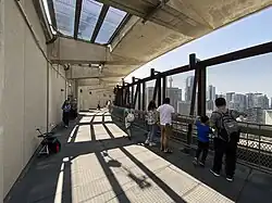 People in outdoor area of building looking out upon city