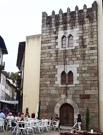 A stone building with white tables and chairs outside