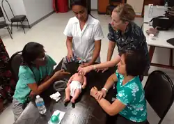 Group of female physicians around a table with a resuscitation mannequin