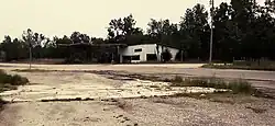 overgrown intersection with abandoned gas station