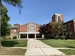 Brick church framed by trees under a sunny sky.