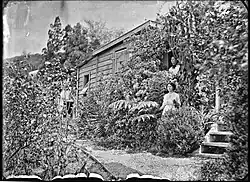 Two women in a garden outside a house in Kohukohu (c. 1900s)