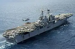 A CH-53E Super Stallion lifting pallets off USS Bataan