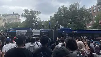 Rioters climbing and standing on top of an M14 bus in Union Square