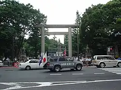 Grey SUV with flags, speakers and white markings.