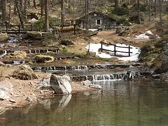 a small body of water with a house in the distance.