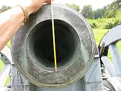 Photo shows the muzzle of a Vallière 8-pouce howitzer with a measuring tape.
