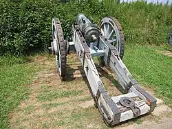Photo shows a short artillery piece mounted on a gun carriage.