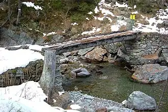 Log bridge in France with dry set stone abutments and a footpath leveled with boards