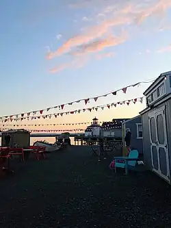 Small shacks along the water front where vendors sell items, although the shacks are closed for the night as the sun sets.