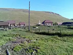 A picture of a hill in Aryshparovo with houses on them with a fence in front of the houses
