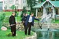 George Bush and Vladimir Putin fish from a fish pond, while an aide holds a landing net