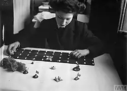 A Wren organising game materials. The wooden pieces represent escort ships, the black board with white shapes represents a convoy, the wire wool represents smoke.