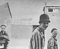 Liberated Jewish prisoners – one wearing a German Stahlhelm – smiling for the camera