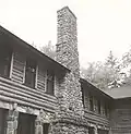 Photograph of Wickyup, showing one of the cobble chimneys and the log construction.